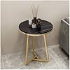 Small round table with black marble top and gold metal frame on a tiled floor.