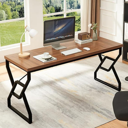 Wooden desk with computer setup in a bright room with large windows.