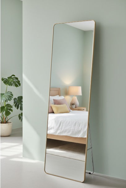 Full-length mirror leaning against a wall in a bedroom setting.